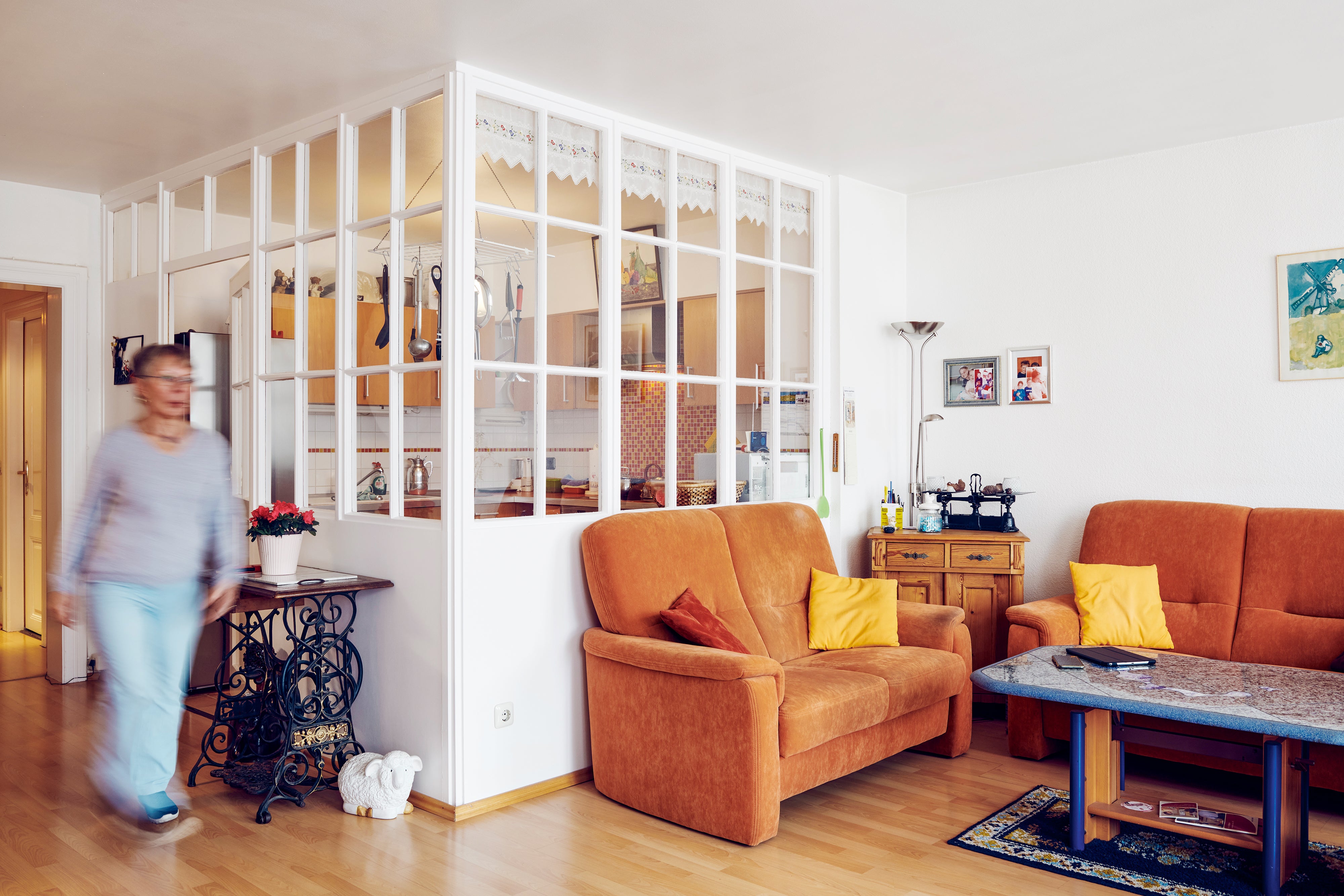 Person geht in einer gemütlichen Wohnzimmer mit Küche im Hintergrund.