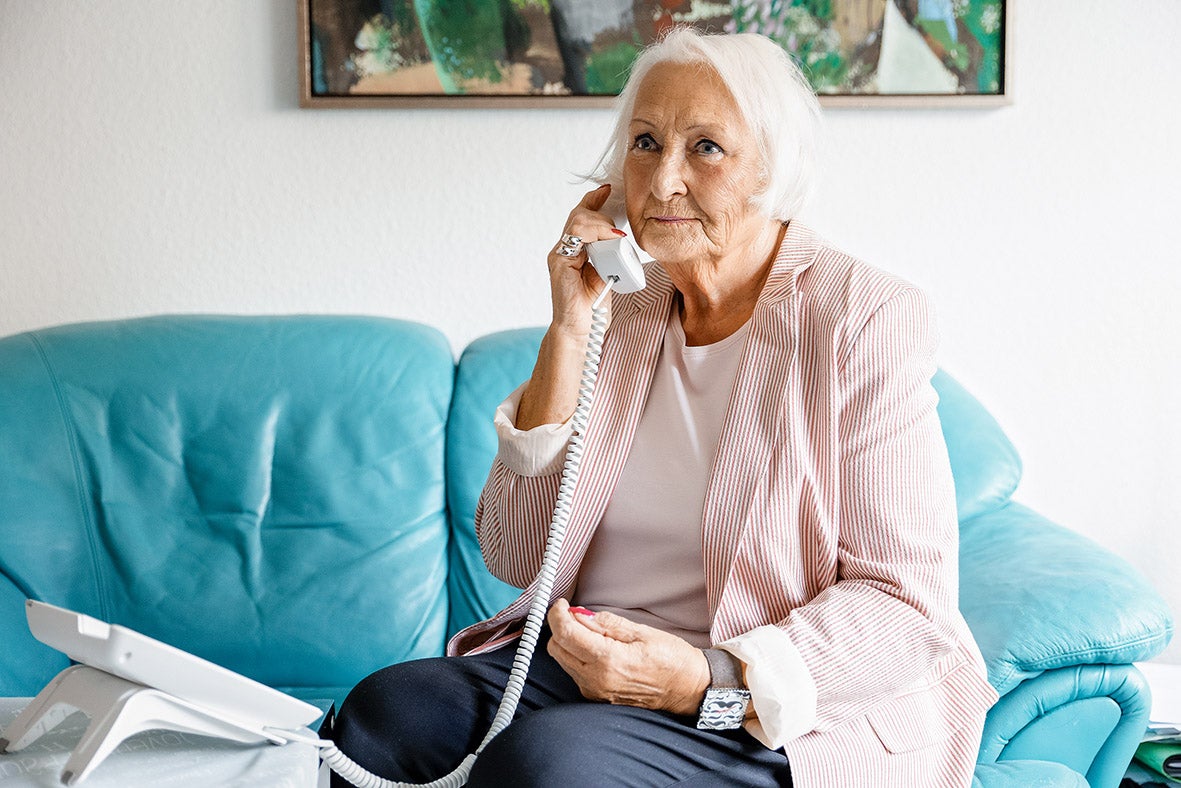 Frau telefoniert auf Sofa im Wohnzimmer.