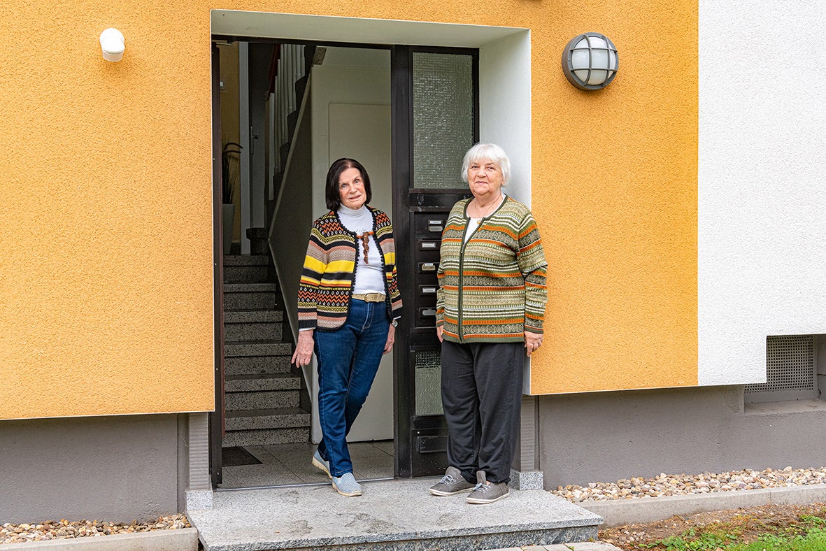 Zwei Frauen stehen in einer Haustür eines gelben Gebäudes.