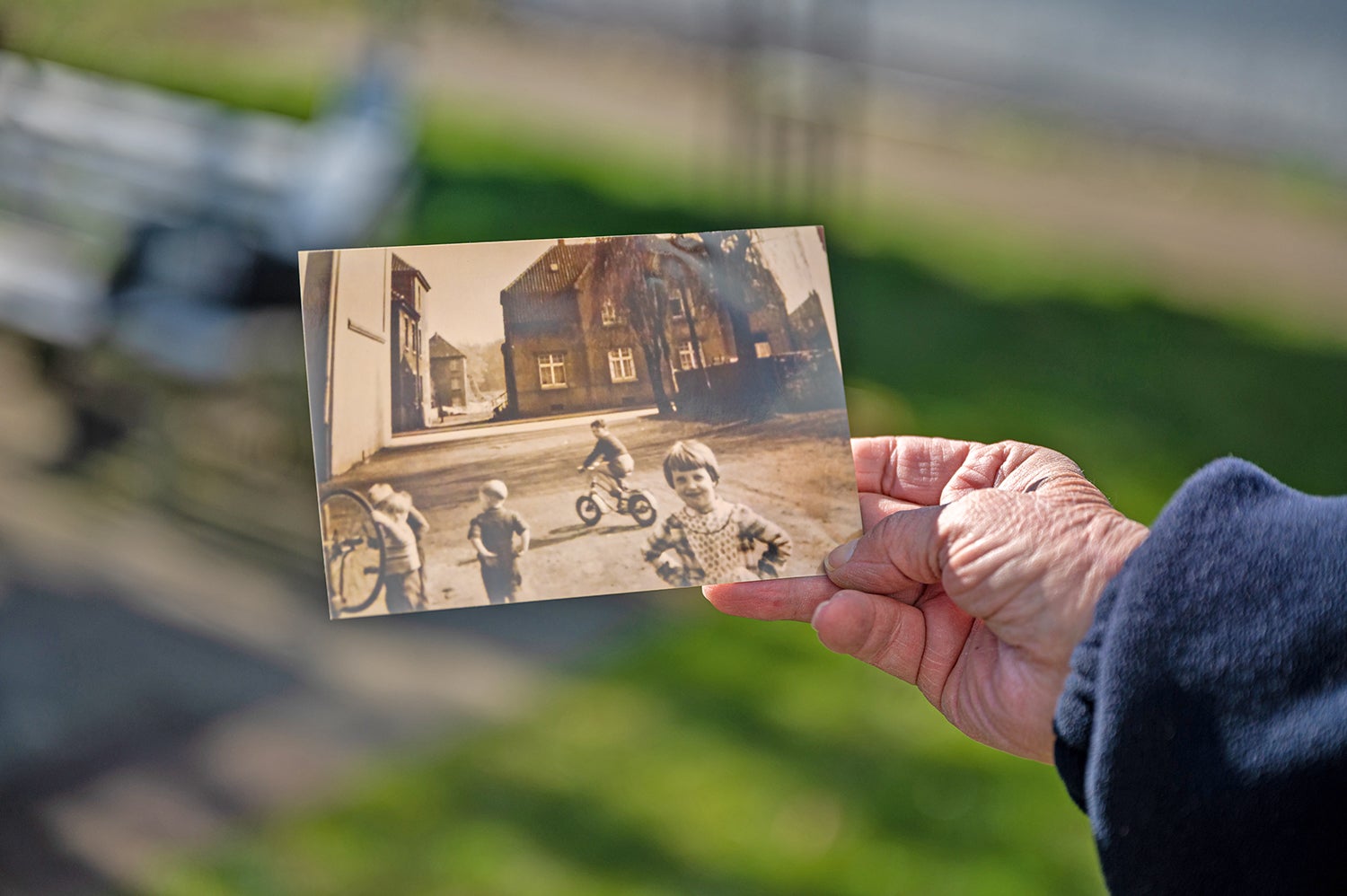 Hand hält ein altes Foto von Kindern, die draußen spielen.