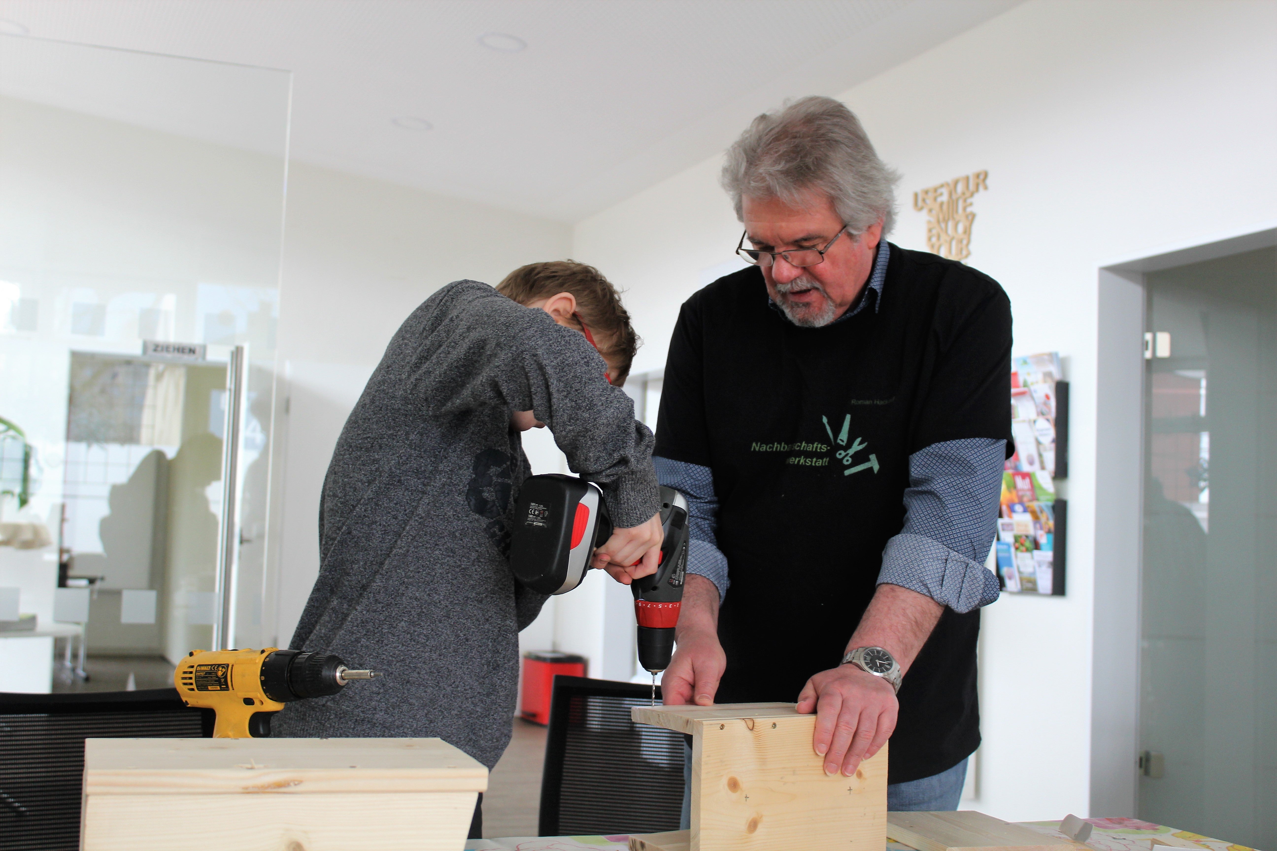 Zwei Personen bauen Nistkästen aus Holz
