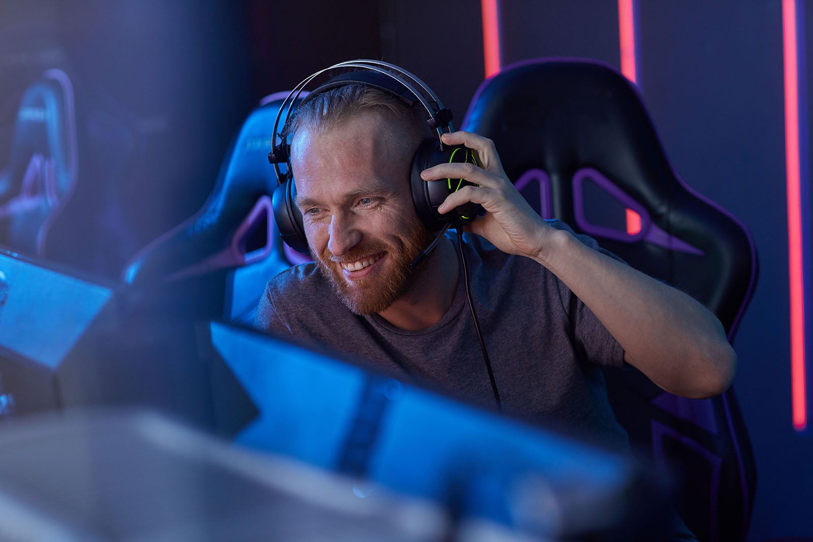 Eine Person mit Headset sitzt lächelnd vor einem Computer.