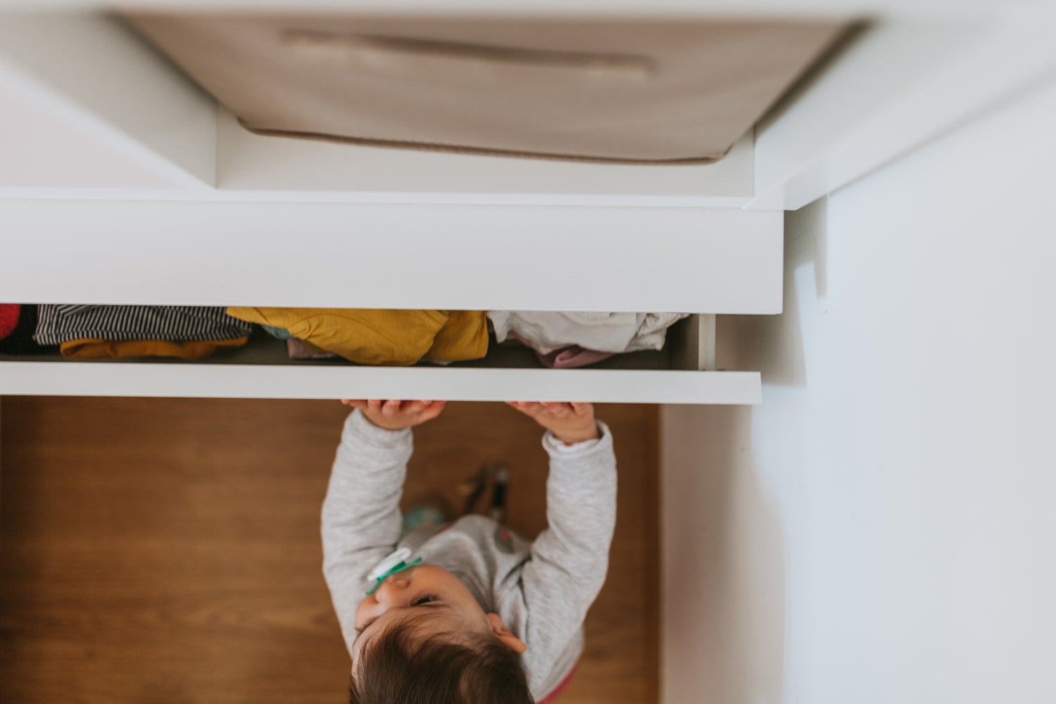 Kind von oben fotografiert steht an einem Schrank.