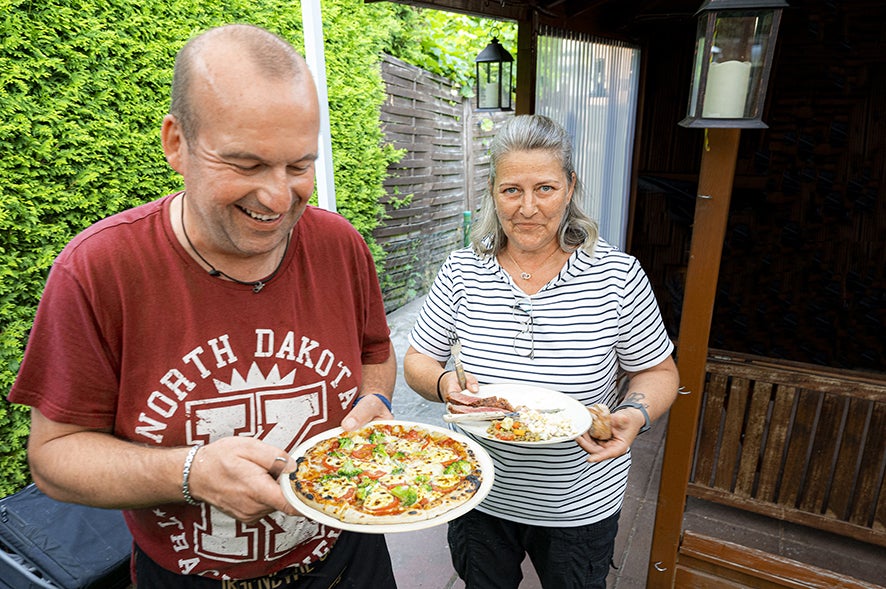 Personen halten Essen im Garten.